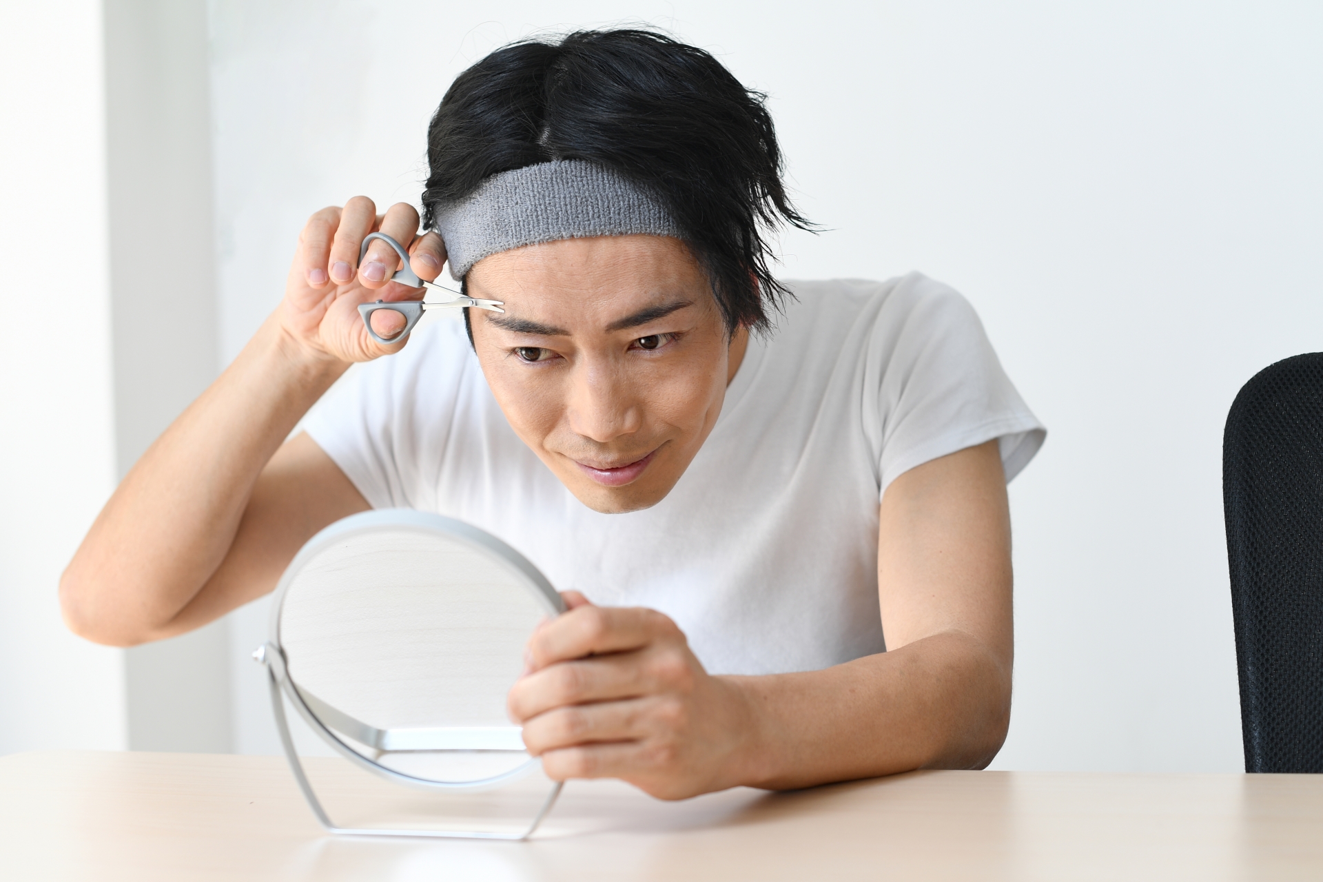 鏡を見ながら眉毛をカットする男性