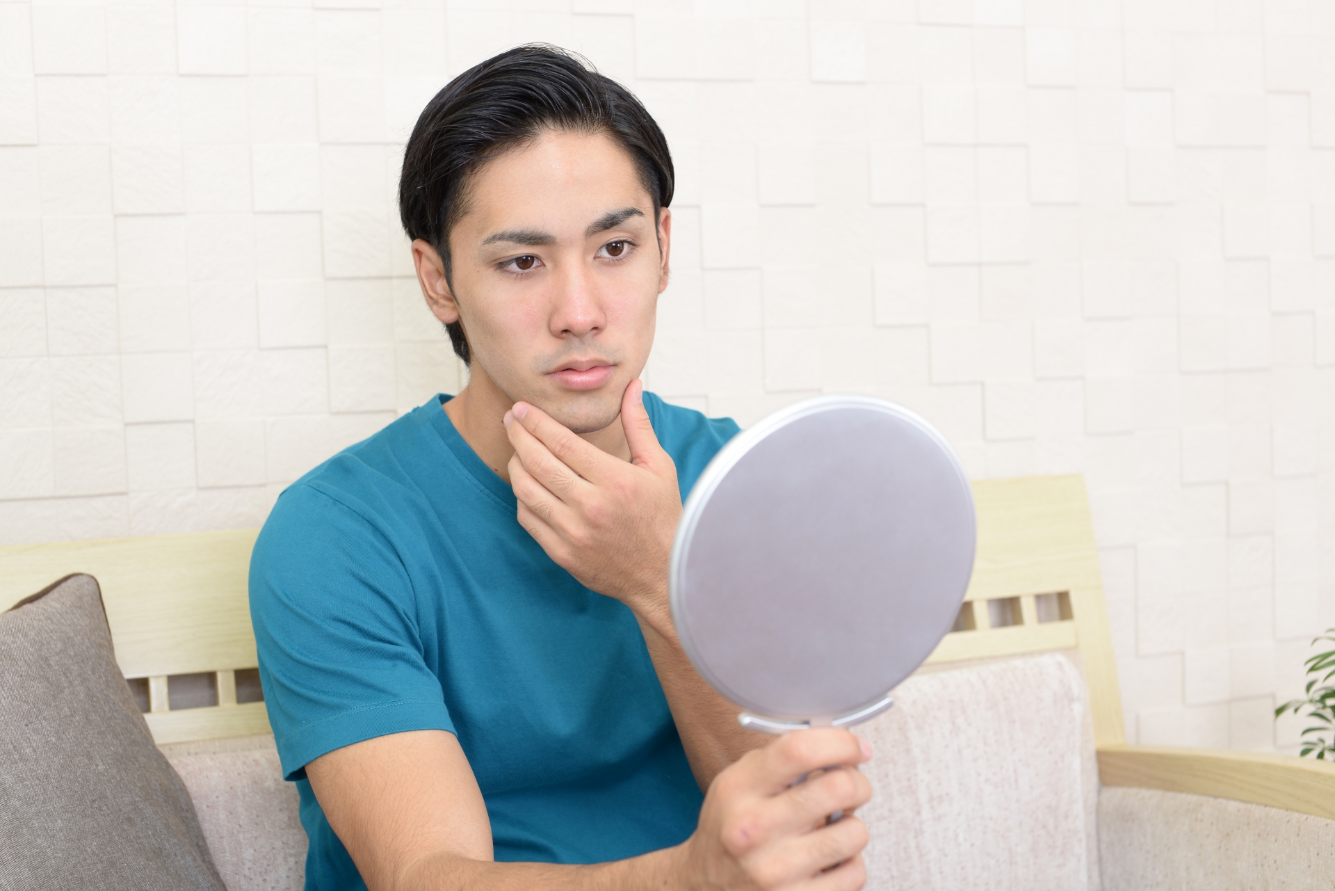 手鏡で顔を確認する男性