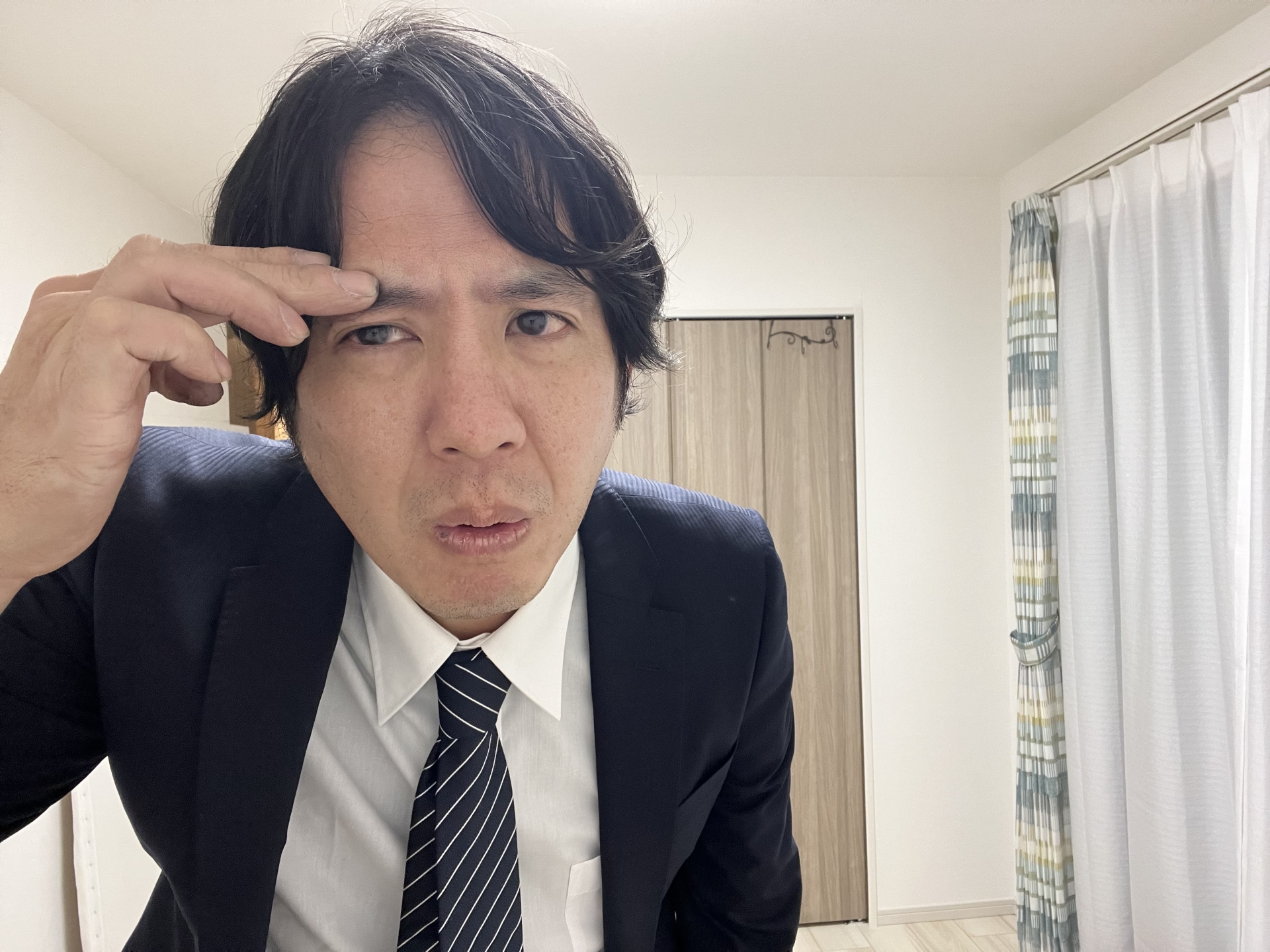 眉毛を気にするスーツ姿の男性