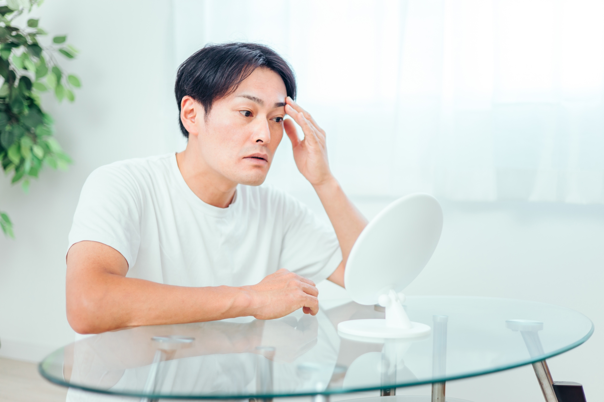 鏡を見ながら眉毛を整える男性